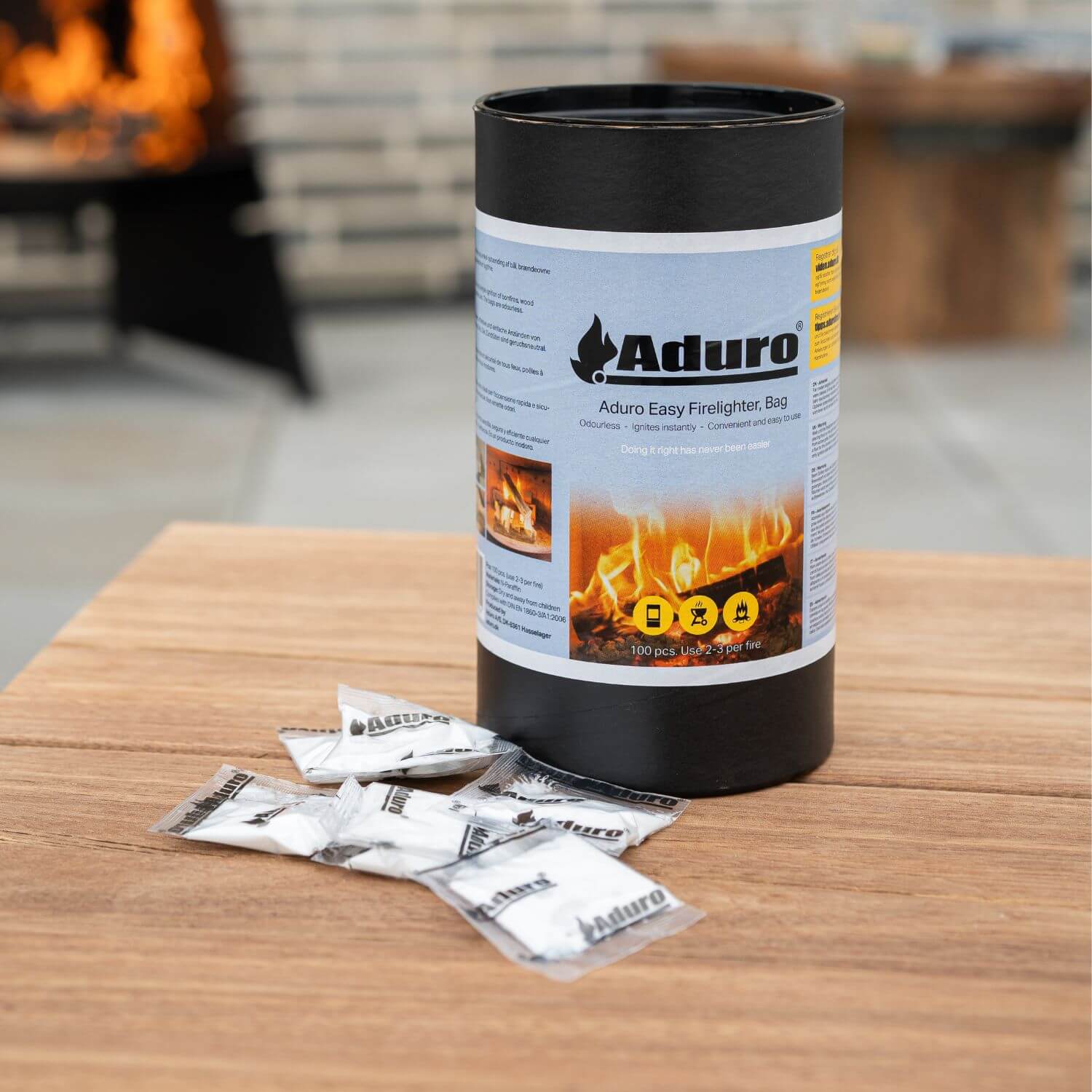 Aduro Easy Firelighter optændingsposer i beholder med tændposer placeret på træbord foran pejs