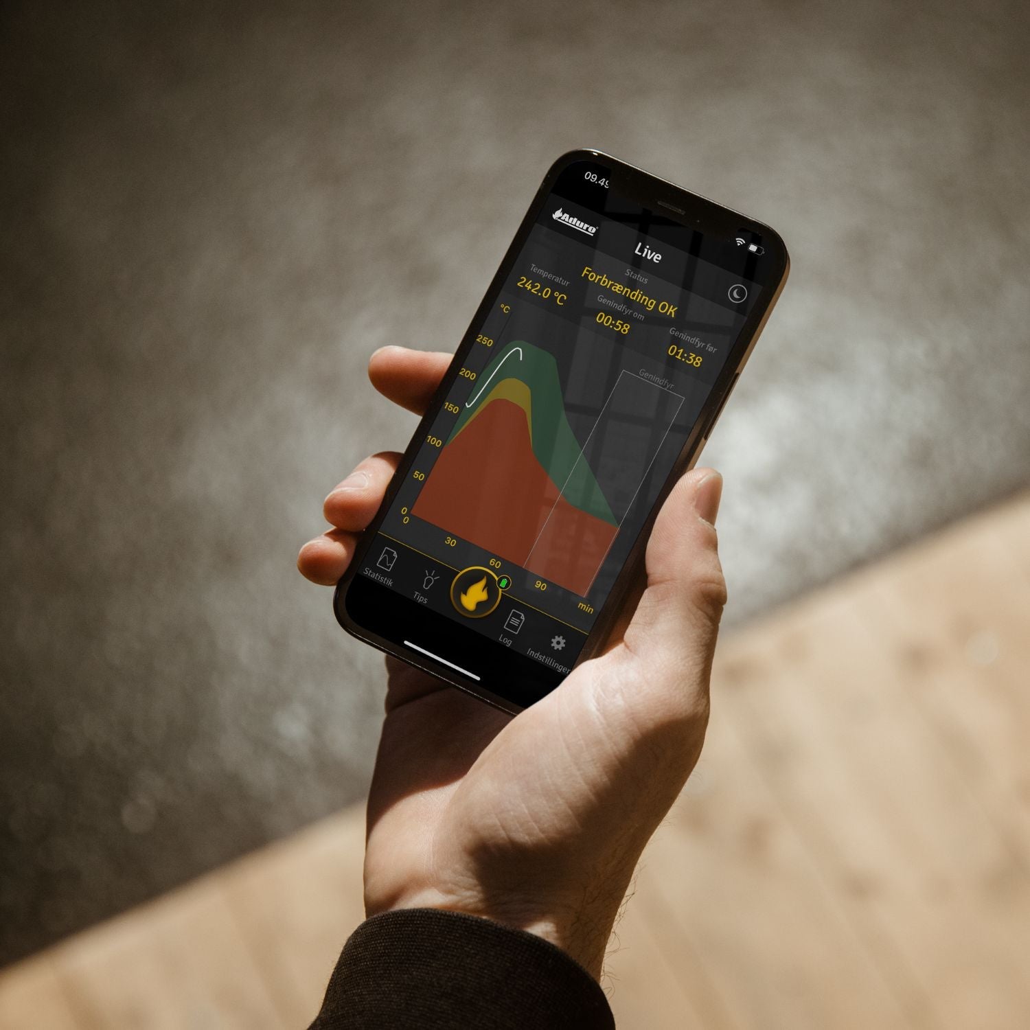 Person bruger Aduro app på smartphone til overvågning af brændeovn