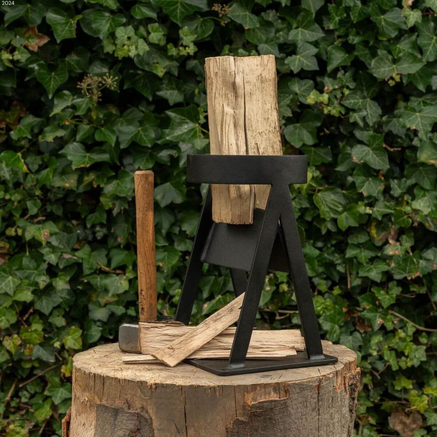 Kindling splitter i metal med et stykke brænde i med en økse ved siden af