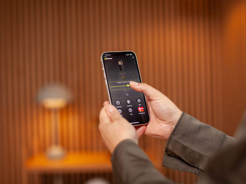 Person holder smartphone og tænder op i hybridovn gennem en app