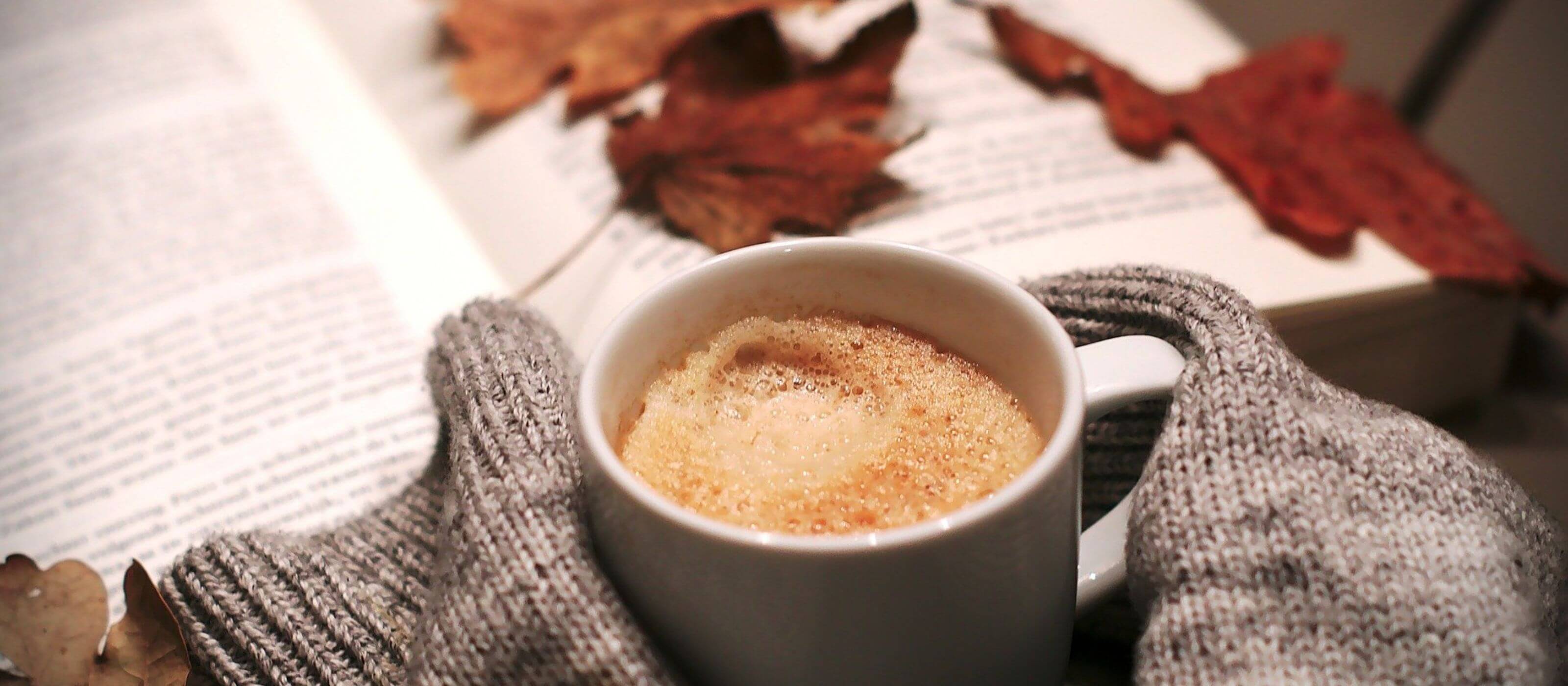 Varm kop kaffe med bog i baggrunden