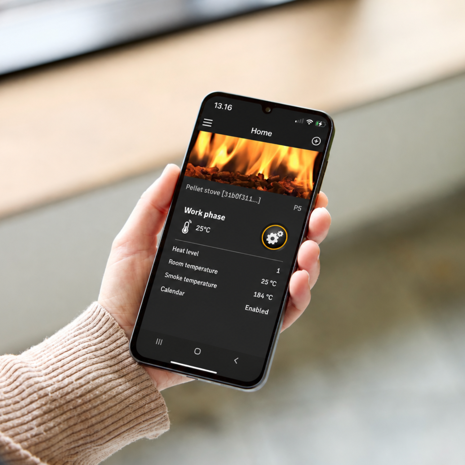 Hånd med mobiltelefon i hånden med Aduro Pellet Stove app