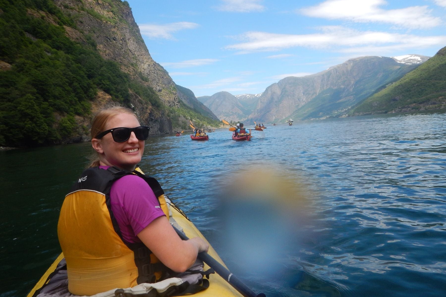 Person sidder i kajak på flod og kigger ind i kameraret